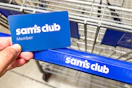 hand holding a sams club membership card over shopping cart