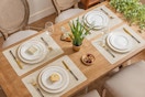 View from above of a table set with plates and silverware. Each place setting has a beige vinyl placemat underneath. They're heat-resistant.