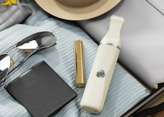 a bikini trimmer in a suitcase with clothes, makeup, and sunglasses