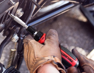 a person using a ratcheting screwdriver on a machine