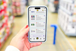 Hand holding smartphone displaying 1-clip coupons in the KCL app