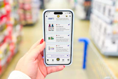 Hand holding smartphone displaying 1-clip coupons in the KCL app