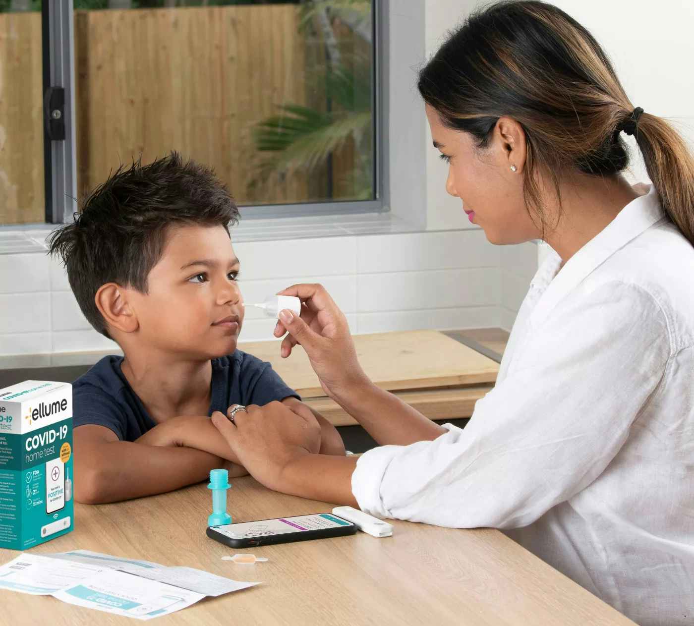 A mother giving her son an at-home covid test with nasal swab