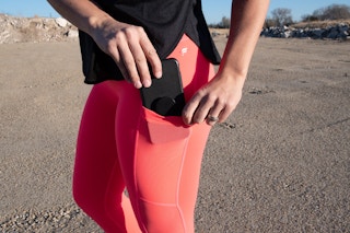 woman wearing pink Fabletics Mila capri pants with cell phone in pocket