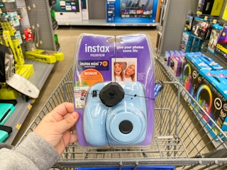 hand holding fuji film instax camera bundle over walmart cart
