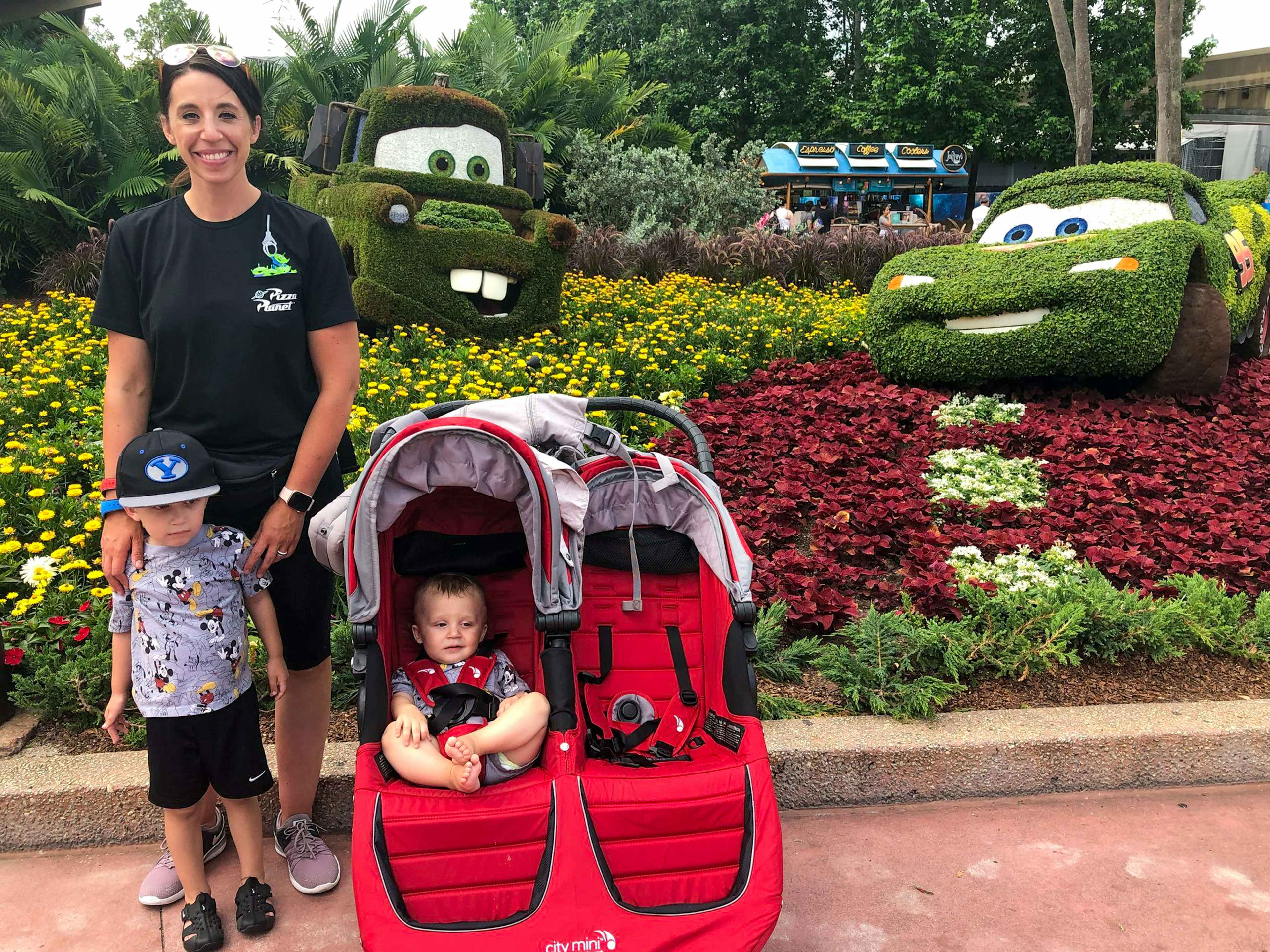 a mom and kids standing next to characters from Cars