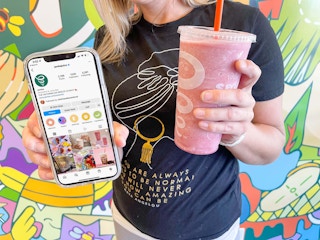 woman holding cell phone with jamba juice cell phone and smoothie in other hand