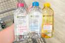 person holding 3 bottles of garnier micellar water over a cart