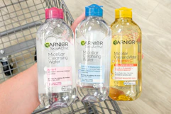 person holding 3 bottles of garnier micellar water over a cart