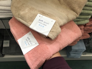 A person taking some Sunham soft spun towels from a shelf at Macy's