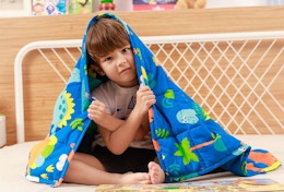 a little kid under a blue dinosaur blanket