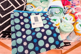 A hand taking a The Big One beach towel off of a shelf at Kohls