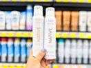 hand holding two bottle of Native whole body deodorant spray