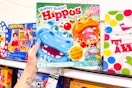 person grabbing a hungry hungry hippos board game off the shelf