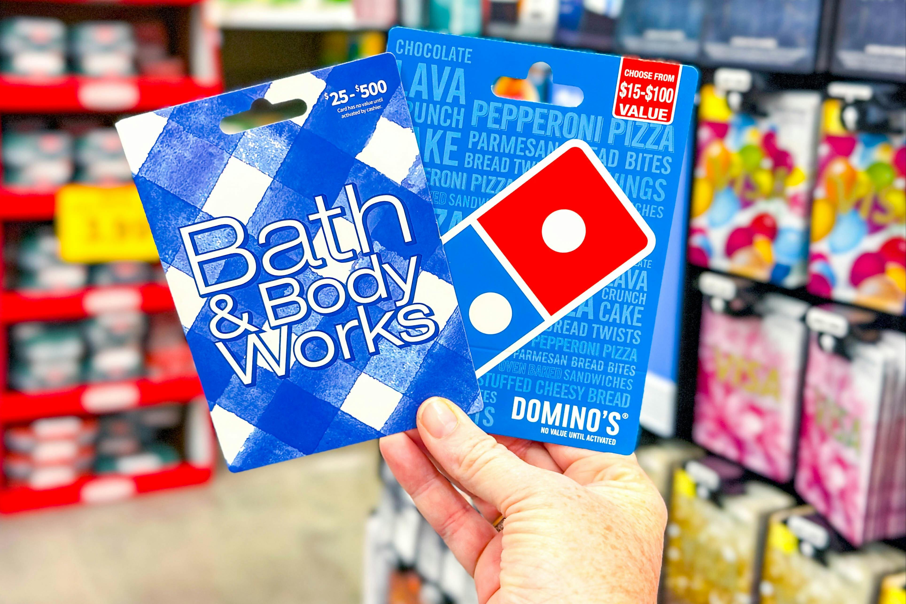 hand holding bath and body works and dominos gift cards