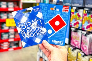 hand holding bath and body works and dominos gift cards