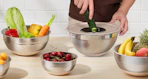 stainless steel bowls on a counter full of fruits and vegetables