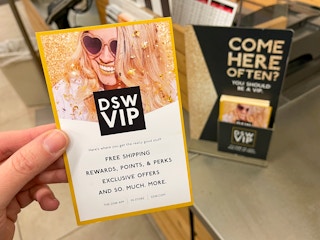 A person holding up a DSW VIP info card near checkout.