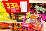 kroger halloween candy sale sign and a person's hand holding up a bag of candy 