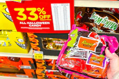 kroger halloween candy sale sign and a person's hand holding up a bag of candy 