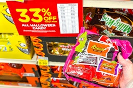 kroger halloween candy sale sign and a person's hand holding up a bag of candy 