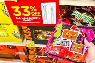 kroger halloween candy sale sign and a person's hand holding up a bag of candy