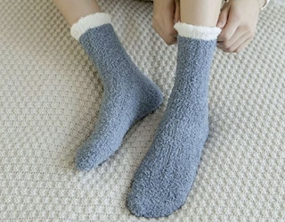 A woman pulling on socks while laying down.