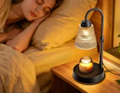 a candle warmer lamp on a nightstand next to a bed