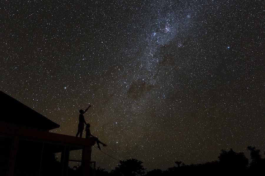 Two people together on a roof looking at stars