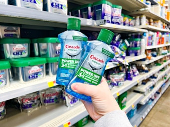hand holding two bottles of Cascade Rinse Aid in the Cascade area