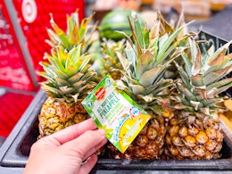 hand grabbing a del monte fresh pineapple off a target shelf