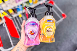 person holding 2 softsoap hand soaps over a cart