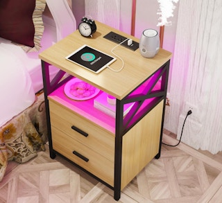 a nightstand with a pink LED light in a room charging a tablet 