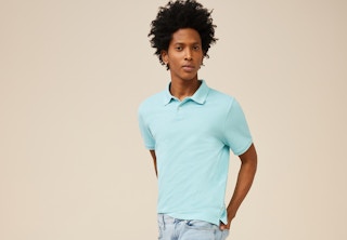 stock photo of man wearing free assembly aqua polo shirt against a tan background