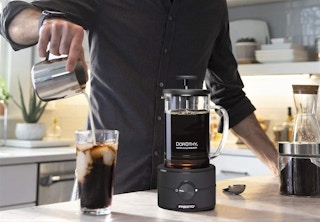 A man pouring iced coffee into a cup, next to his Presto cold brewer.