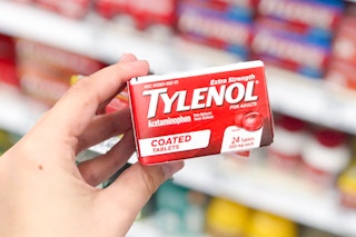hand holding tylenol box in front of shelf