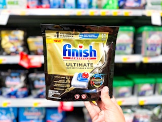 Holding a bag of Finish Ultimate Dishwasher Detergent