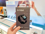 a hand holding a Fitbit in a box