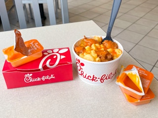 A Buffalo chicken macaroni and cheese secret menu item sitting on a table inside chick-fil-a.