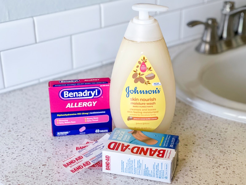 A box of Benedryl, a bottle of Johnson's no tear body wash, and an open pack of Band-Aids sitting on a bathroom counter.