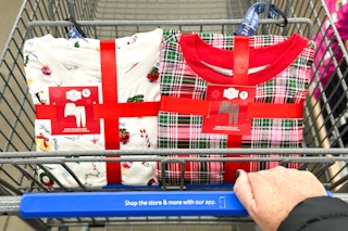 hand pushing walmart cart with two sets of holiday time womens pajamas
