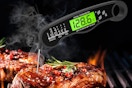 a digital thermometer in a piece of meat on a grill