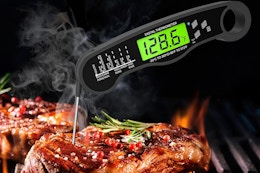 a digital thermometer in a piece of meat on a grill