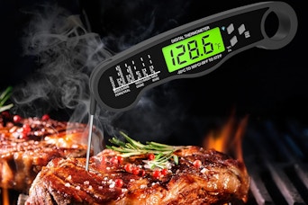 a digital thermometer in a piece of meat on a grill