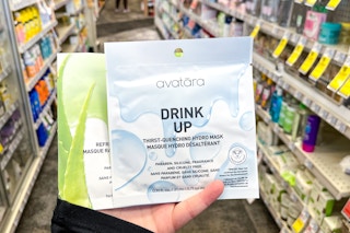 person holding 2 avatara face masks in an aisle