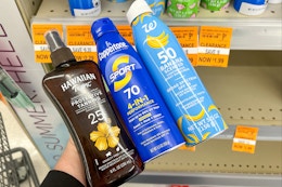 person holding 3 sunscreen bottles