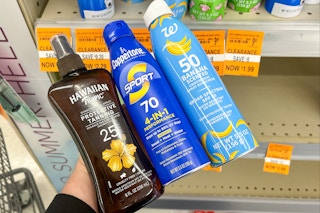 person holding 3 sunscreen bottles