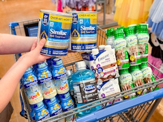 hand holding similac with pediasure pedialyte ensure and glucerna in walmart cart