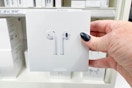 hand holding a pair of apple airpods in front of a target display