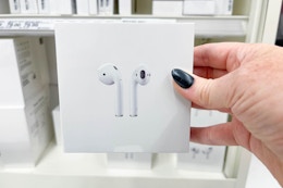 hand holding a pair of apple airpods in front of a target display